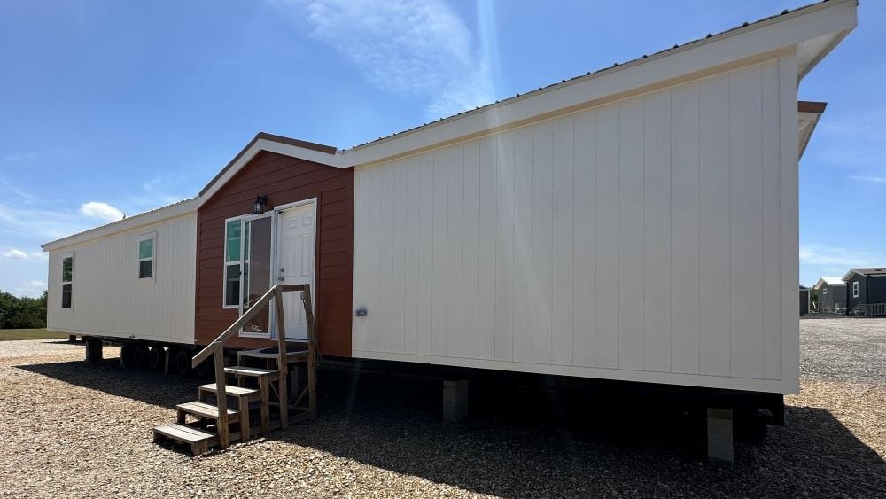 Manufactured home set on concrete-block piers before skirting is installed, showing the open base gap