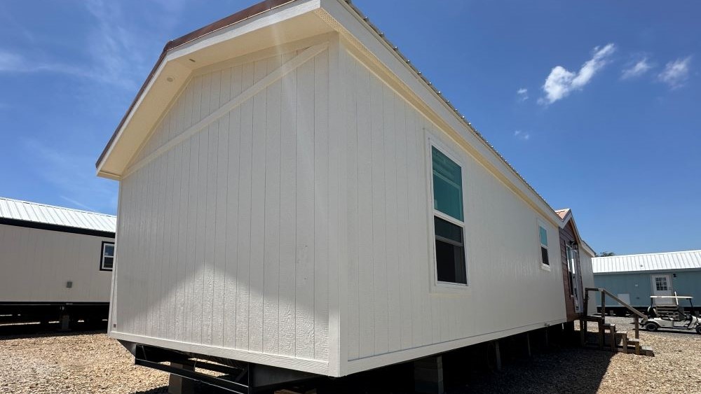 Front exterior view of The Stealth single-section manufactured home with red trim and white siding.